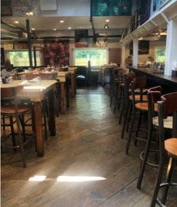 View of one side of bar and some tables in dining area